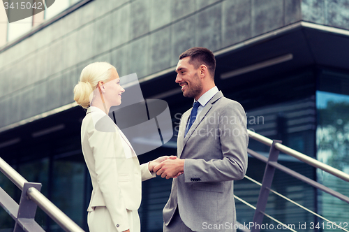 Image of smiling businessmen shaking hands on street