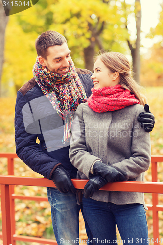 Image of smiling couple hugging on bridge in autumn park