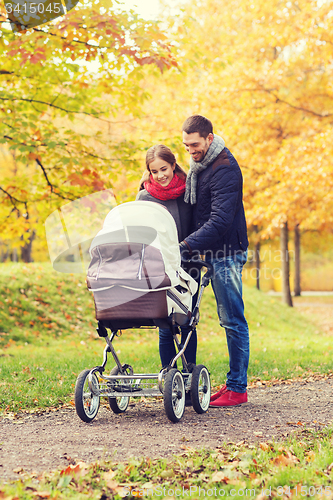 Image of smiling couple with baby pram in autumn park