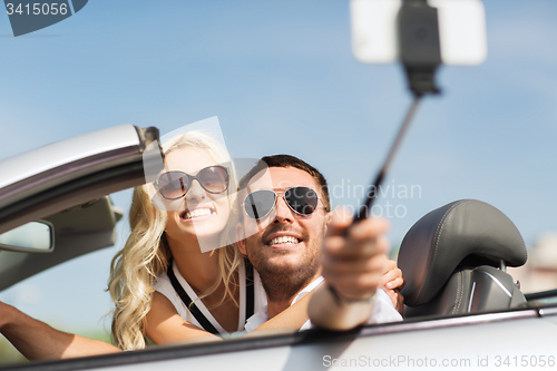 Image of happy couple in car taking selfie with smartphone