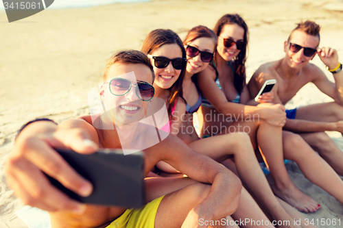 Image of friends with smartphones on beach