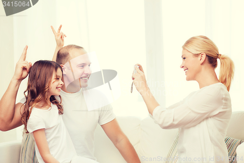 Image of happy mother taking picture of father and daughter