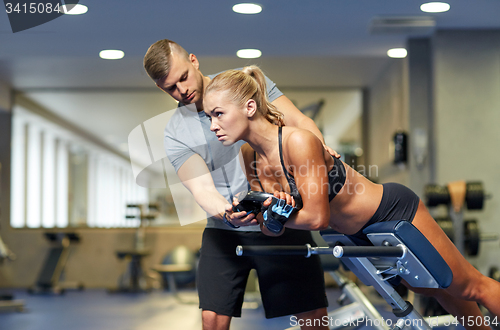 Image of woman with personal trainer flexing muscles in gym