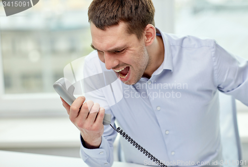 Image of furious businessman calling on phone in office