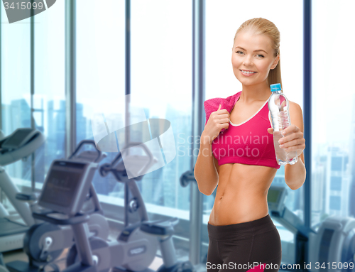 Image of happy woman with bottle of water and towel in gym