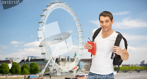 Image of happy young man with backpack and book travelling