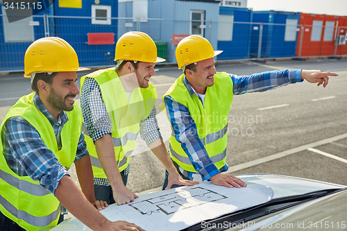 Image of close up of builders with blueprint on car hood