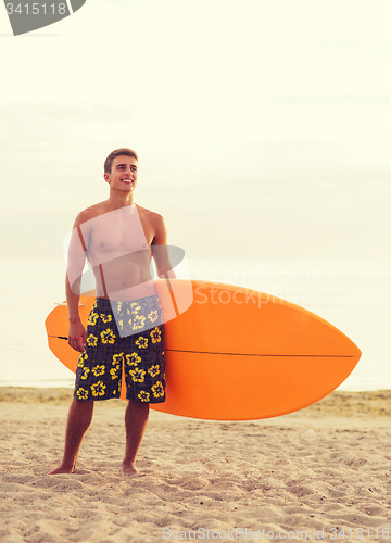 Image of smiling young man with surfboard on beach