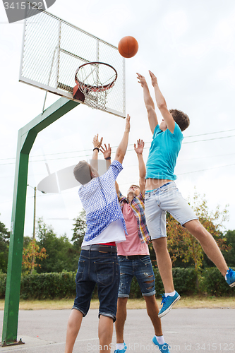 Image of group of happy teenage friends playing basketball