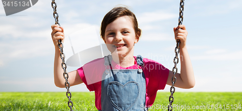 Image of happy little girl swinging on swing outdoors