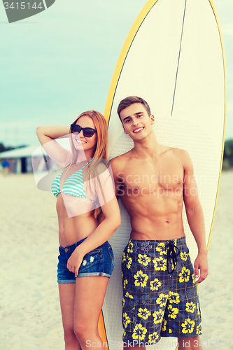 Image of smiling couple in sunglasses with surfs on beach