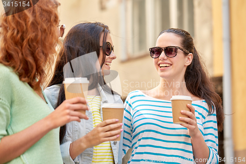 Image of happy young women drinking coffee on city street