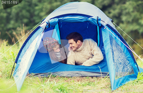 Image of smiling couple of tourists looking out from tent