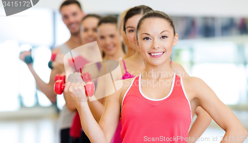 Image of group of smiling people with dumbbells in the gym