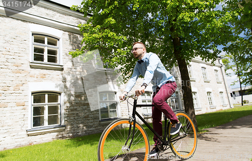 Image of happy young hipster man riding fixed gear bike