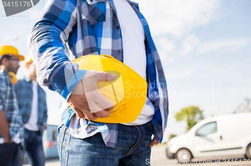 Image of close up of builder holding hardhat at building