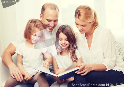 Image of smiling family and two little girls with book