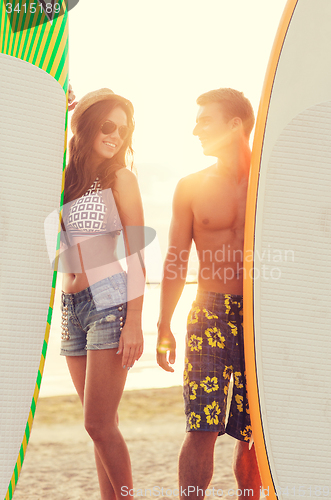 Image of smiling couple in sunglasses with surfs on beach