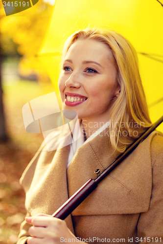 Image of smiling woman with umbrella in autumn park