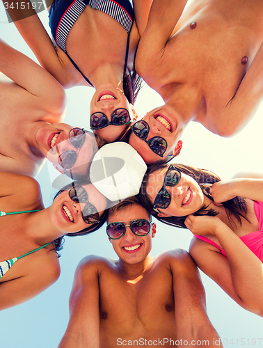 Image of smiling friends in circle on summer beach