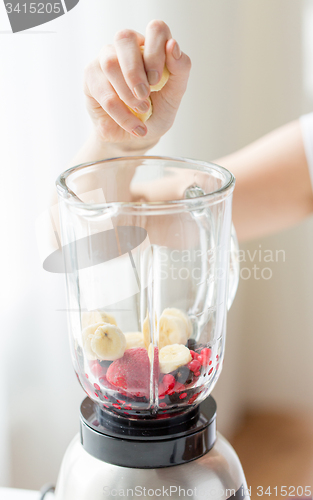 Image of close up of woman hand adding fruits to blender