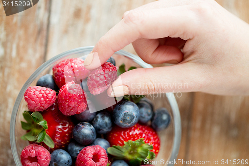 Image of close up of woman hands with berries in glass bowl