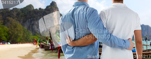 Image of close up of male gay couple hugging on beach