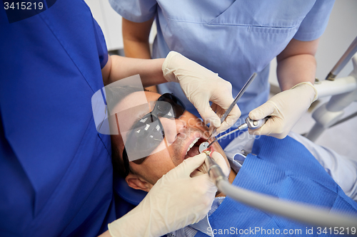 Image of dentist hands treating male patient teeth