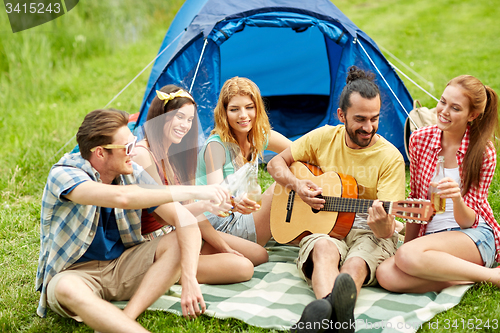 Image of happy friends with drinks and guitar at camping