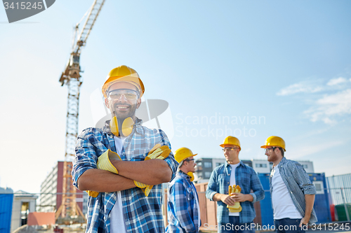 Image of group of smiling builders in hardhats outdoors