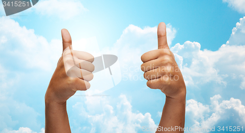 Image of african hands showing thumbs up over blue sky