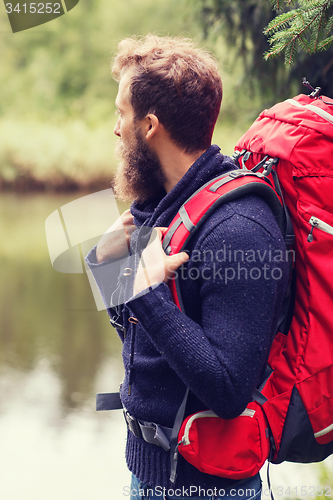 Image of smiling man with beard and backpack hiking