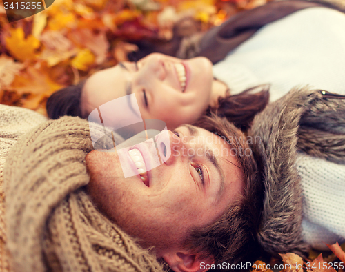 Image of close up of smiling couple lying in autumn park