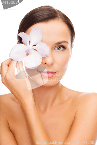 Image of relaxed woman with orchid flower over eye