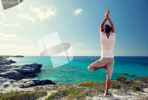 Image of young man making yoga exercises outdoors