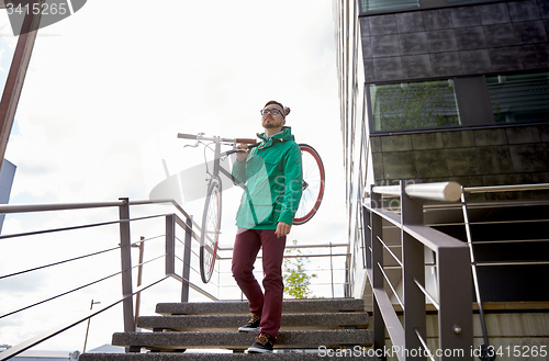 Image of young hipster man carrying fixed gear bike in city