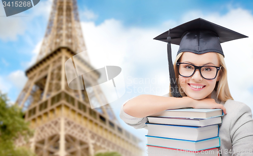 Image of student in trencher with books over eiffel tower