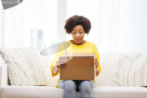 Image of happy african young woman with parcel box at home