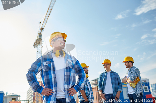 Image of group of smiling builders in hardhats outdoors