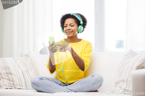 Image of happy african woman with smartphone and headphones