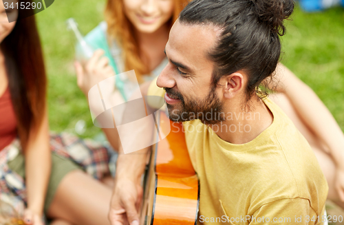 Image of happy man with friends playing guitar at camping