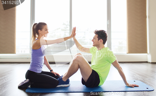 Image of man with personal trainer doing sit ups in gym