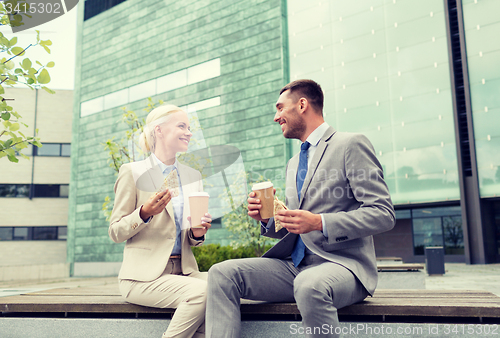 Image of smiling businessmen with paper cups outdoors