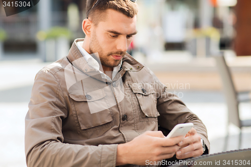 Image of man with smartphone at city street cafe