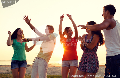 Image of smiling friends dancing on summer beach