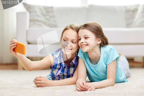 Image of happy girls with smartphone taking selfie at home