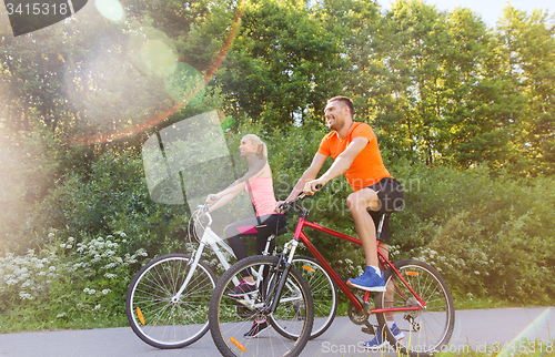 Image of happy couple riding bicycle outdoors