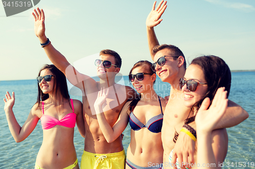 Image of smiling friends in sunglasses on summer beach