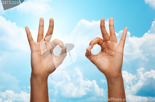 Image of two african hands showing ok sign over blue sky