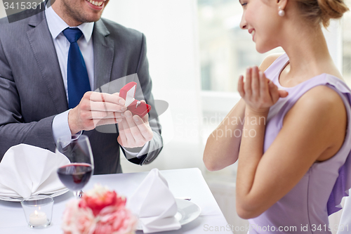 Image of excited young woman and boyfriend giving her ring